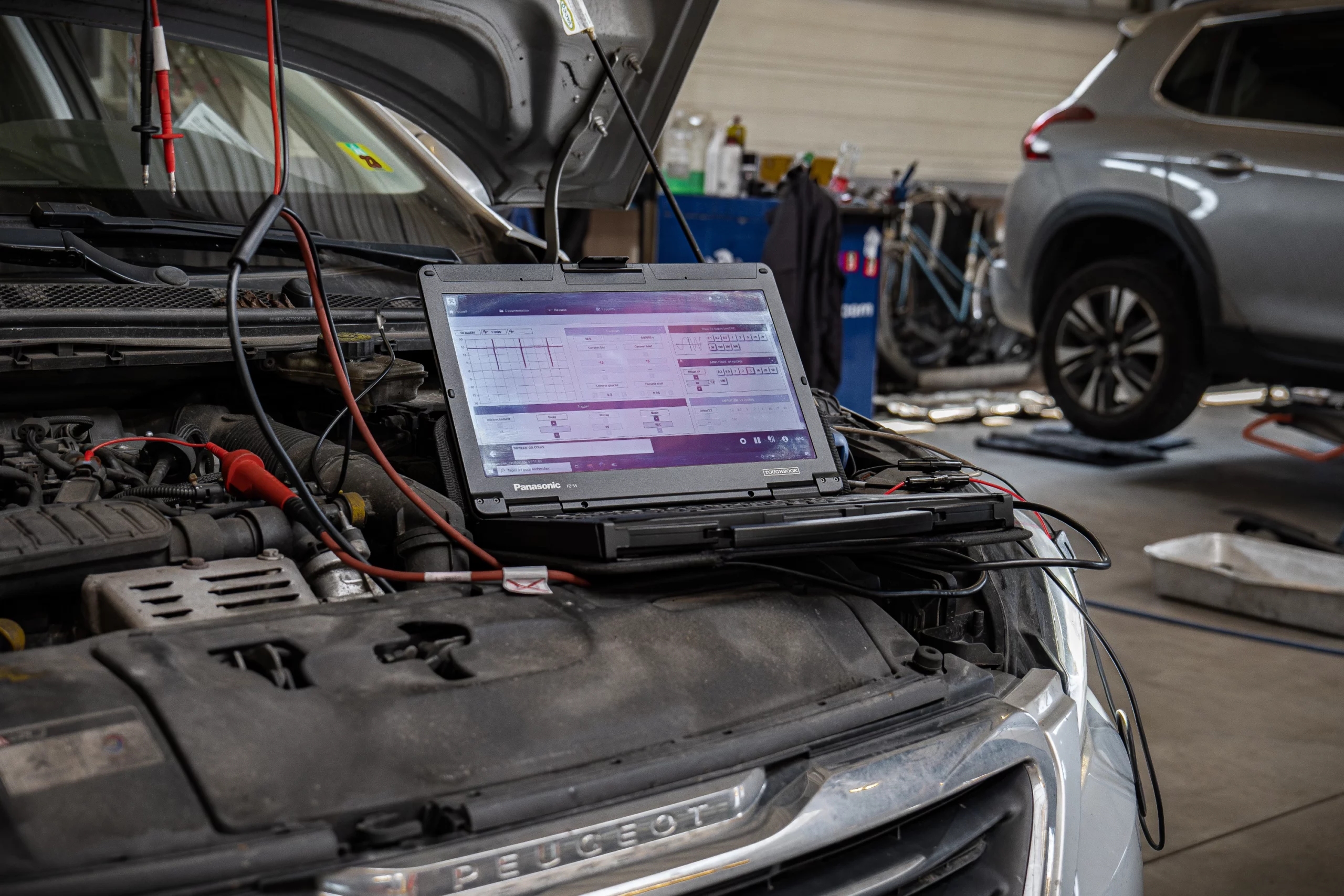 Diagnostic électronique d'une voiture Peugeot avec un ordinateur dans un atelier de réparation.