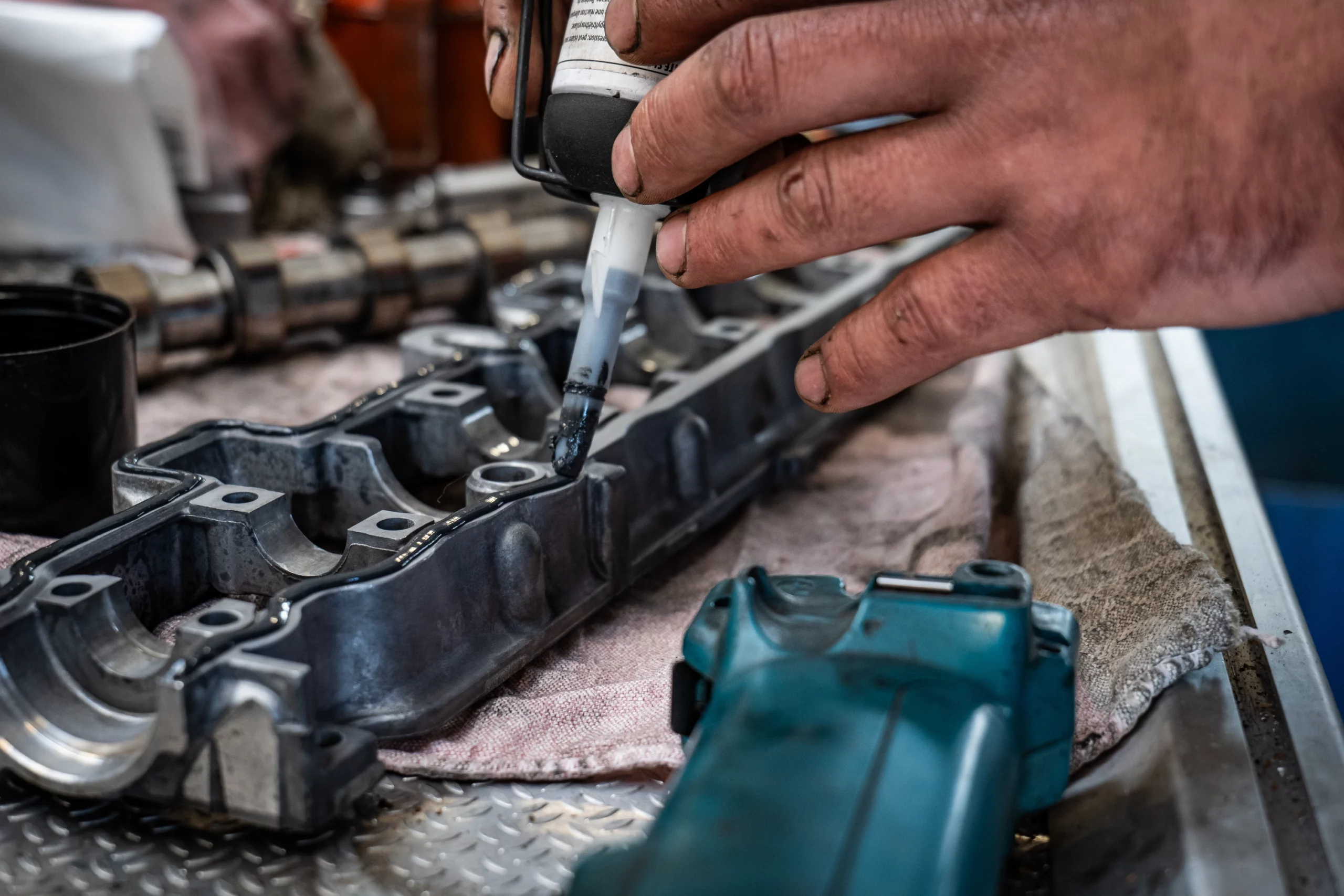 Mécanicien appliquant du lubrifiant sur un composant moteur dans un atelier Peugeot.