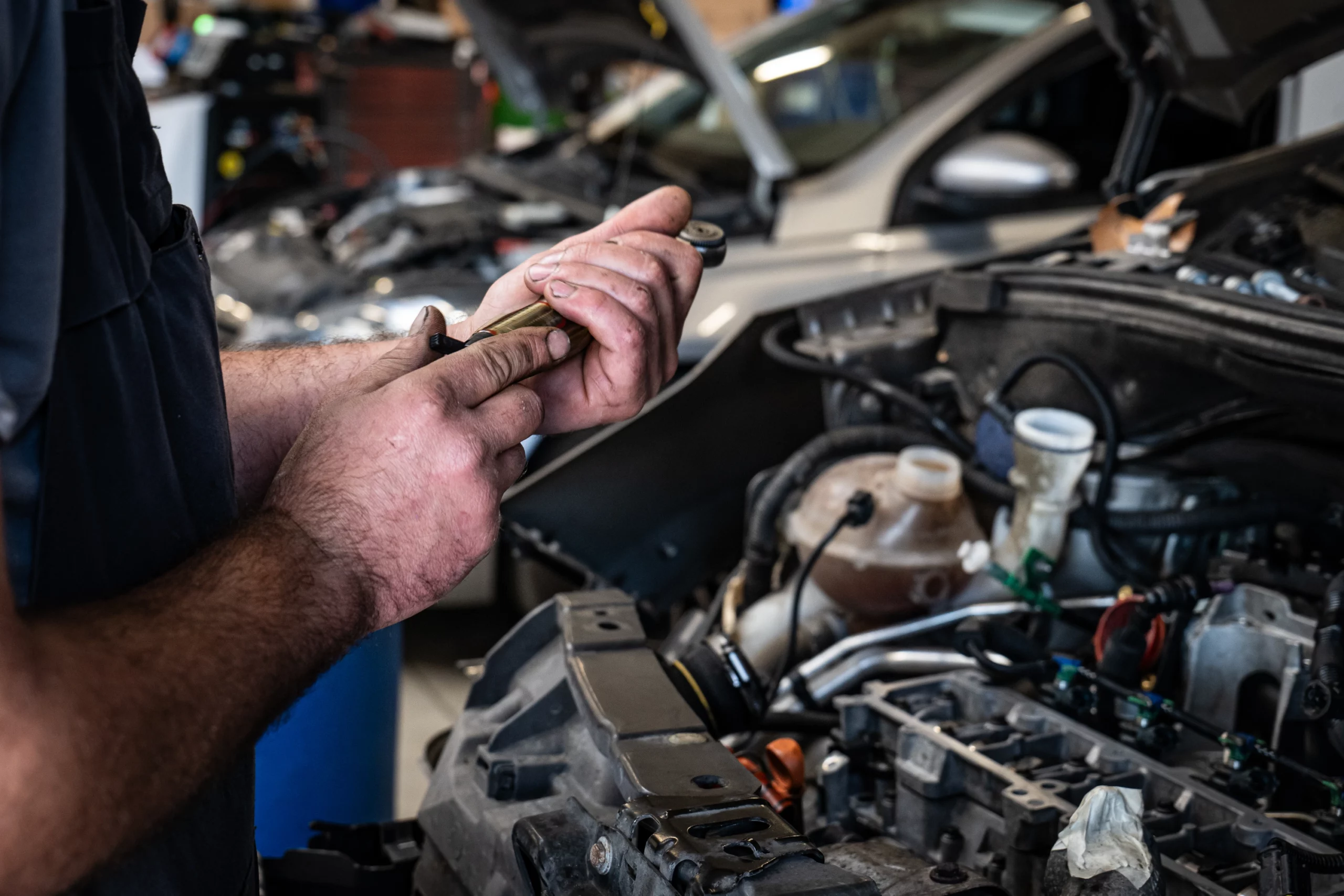 Mécanicien ajustant ses outils pour réparer un moteur Peugeot dans un atelier.