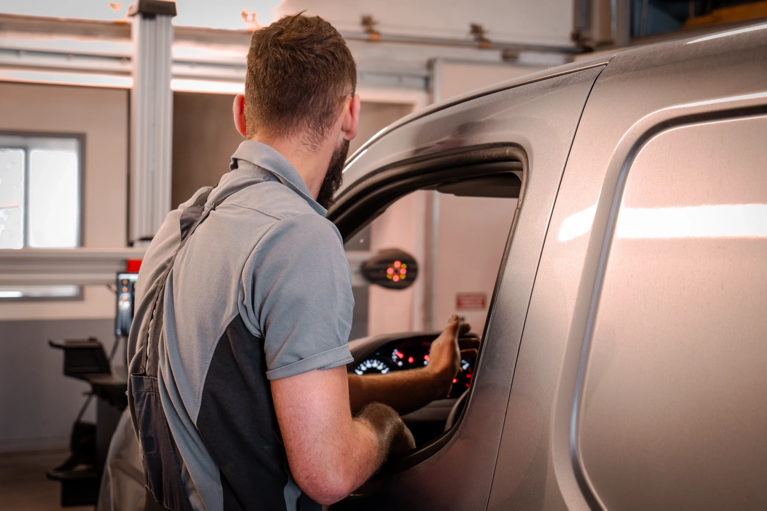 Technicien effectuant une vérification visuelle à l'intérieur d'un véhicule Peugeot dans un atelier.