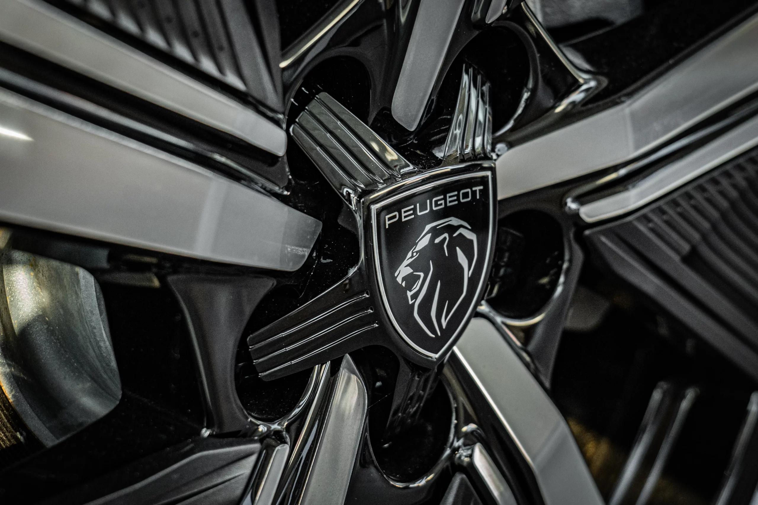 Zoom sur une jante en alliage noir avec logo Peugeot sur un véhicule.