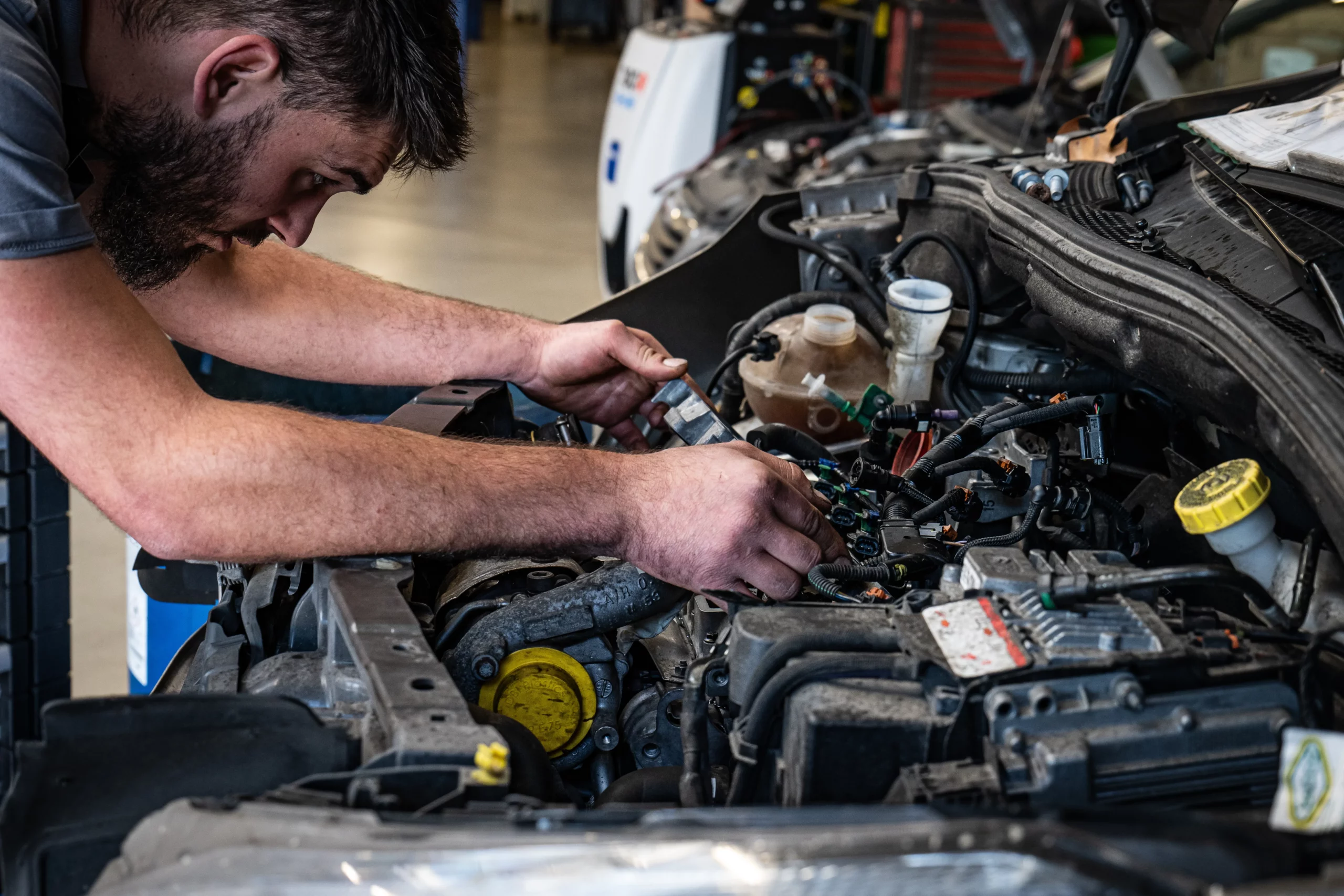 Mécanicien effectuant une réparation sur le moteur d'un véhicule Peugeot.